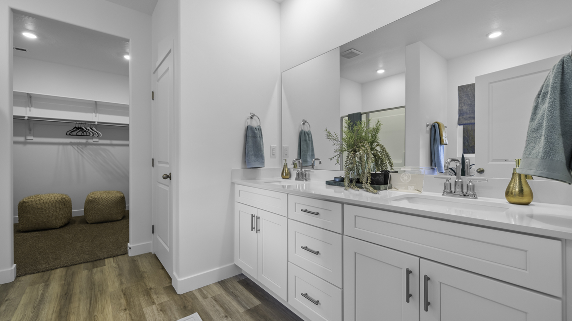 Large primary bathroom with quartz countertops, double sink vanity, and separate walk in shower and garden tub with window