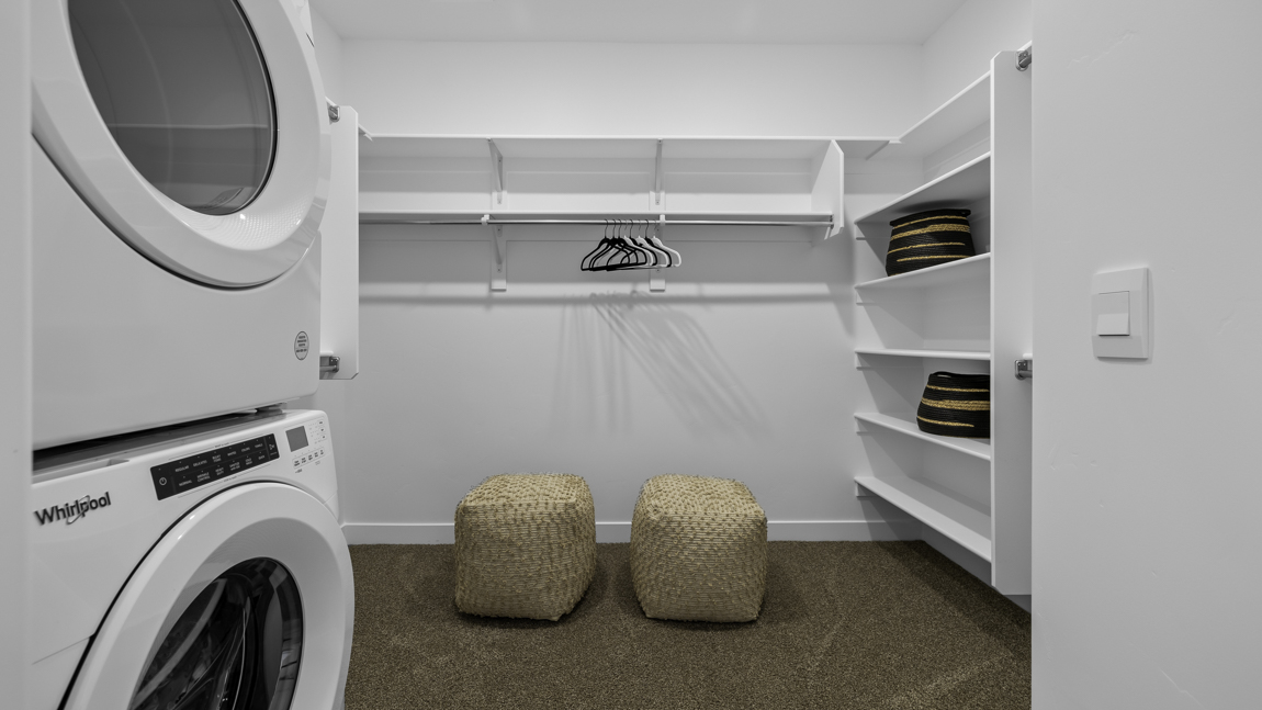 Large walk in closet with built in shelving and stackable washer and dryer