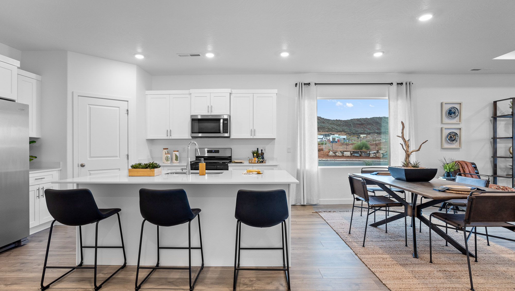 Large kitchen with corner panty, quartz countertops, and stainless steel appliances next to the dining room with an oversized picture window
