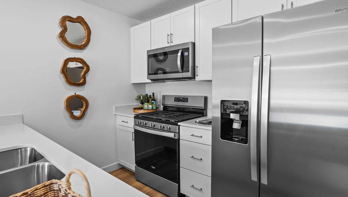 Kitchen with white quartz countertop peninsula with stainless steel appliances and pantry