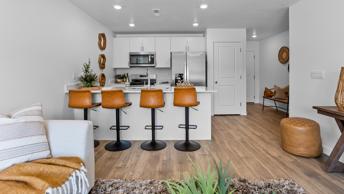 Open floorplan with a family room that opens into a kitchen with white quartz countertops and stainless steel appliances