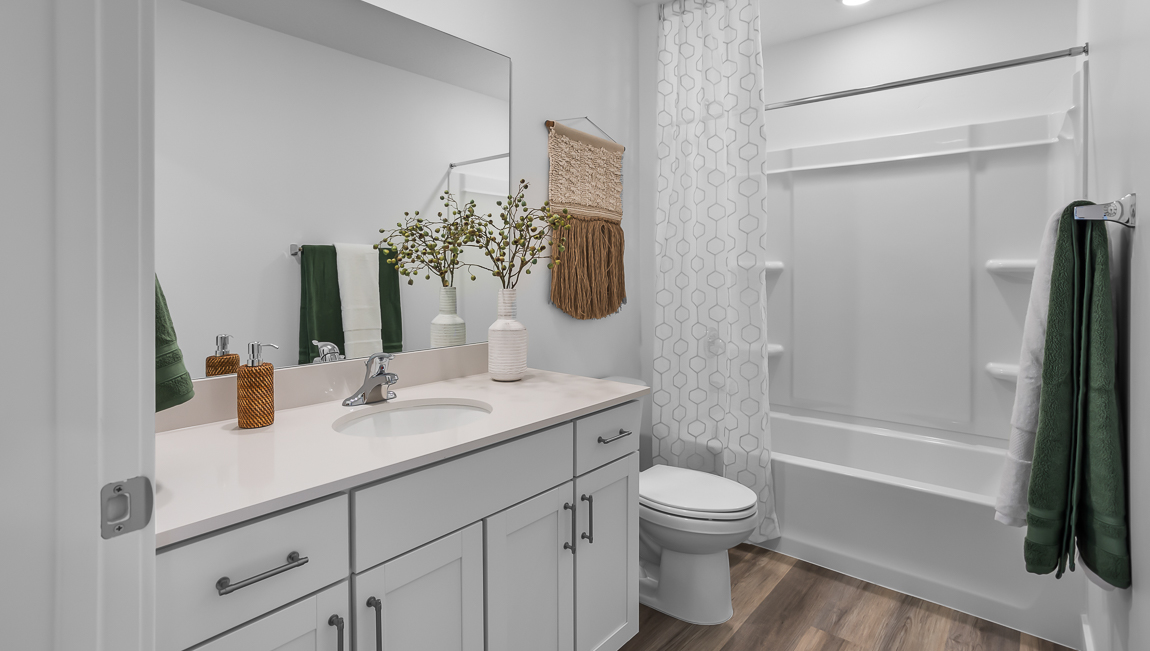 Secondary bathroom with white quartz countertops and tub shower