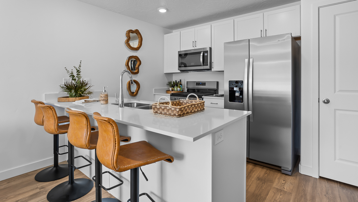 Kitchen with white quartz countertop peninsula with stainless steel appliances and pantry