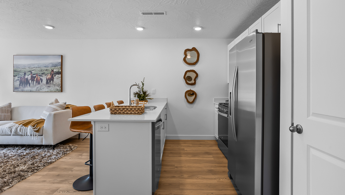 Kitchen with white quartz countertop peninsula with stainless steel appliances and pantry