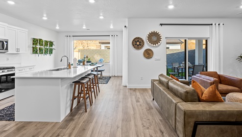 Adjacent to the living room is an expansive kitchen with a large breakfast bar with 3 wide barstools for entertaining and white countertops and cabinets and stainless steel appliances.