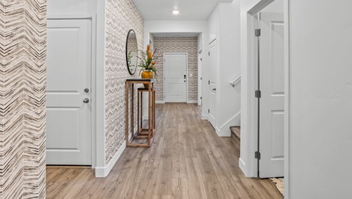 View towards the entryway from the open concept main floor living space with stairs to the right to the second floor living spaces at the model home in Long Valley.