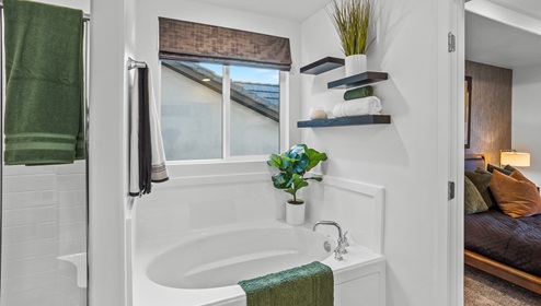 A view of the sizable primary suite double sink with white cabinets and countertops and large mirror.