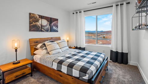 A stylish secondary bedroom with two side tables and a large window the Stillwater model home in Long Valley.