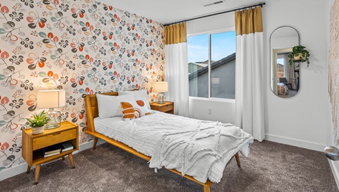 A stunning secondary bedroom with a large bed, desk, two side tables and a large window.