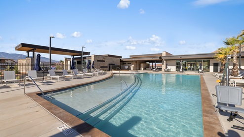Another view of the pool lined with lounge chairs, umbrellas and palm trees.