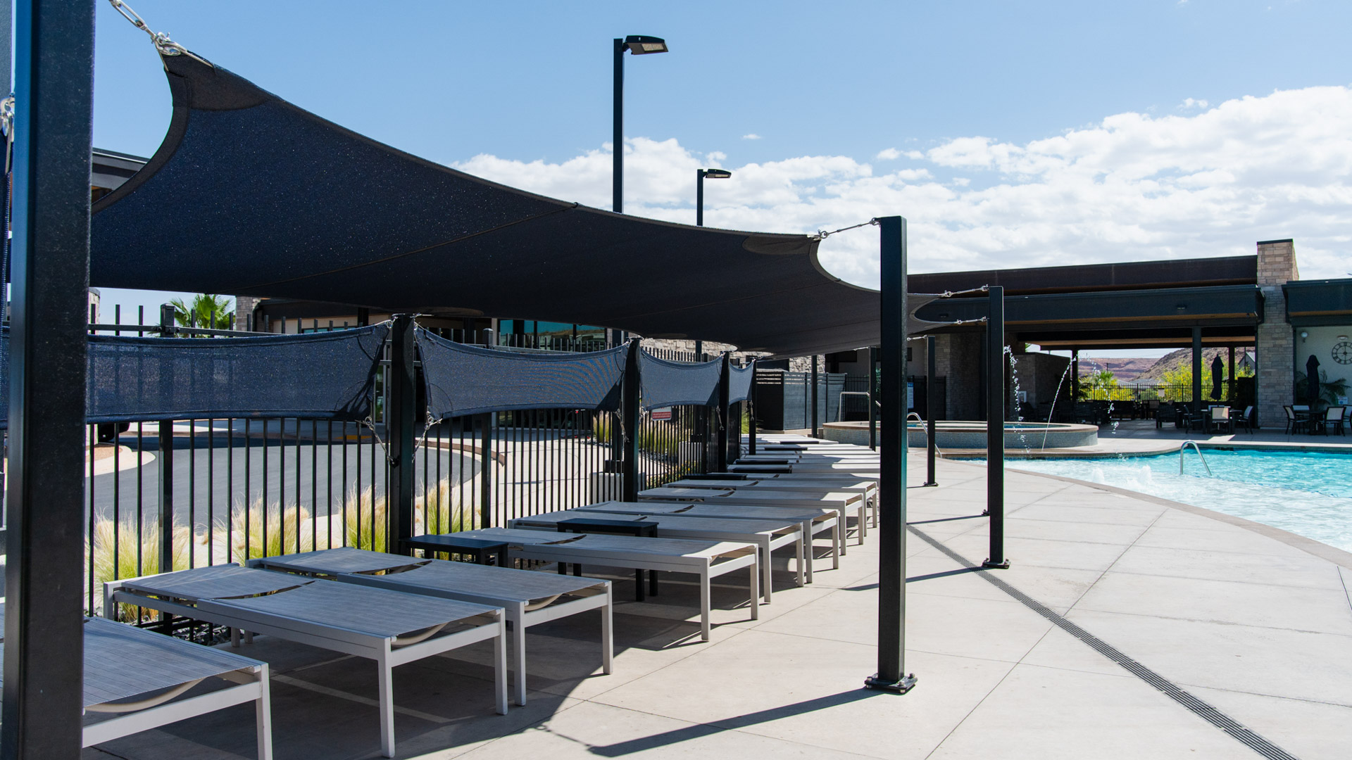 Lounge chairs under shaded area near pool.