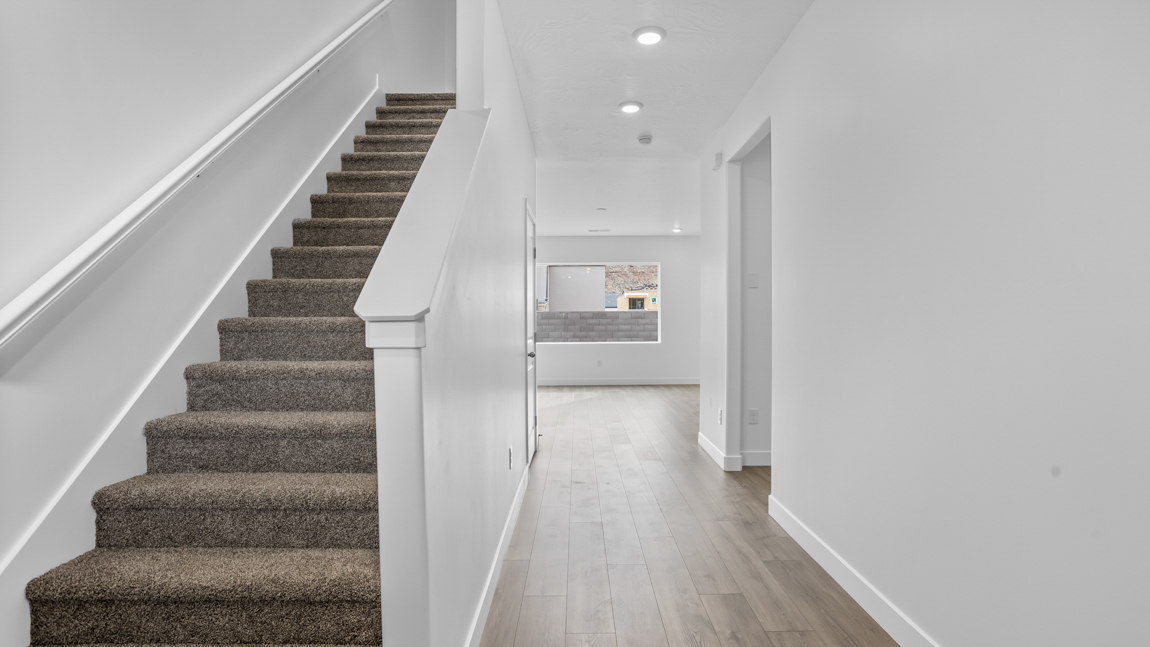 Entry of the home with a wide staircare leading to the second floor, and an extra-wide hallway leading to the main floor living area.
