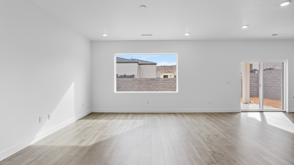 Large family room with oversized window, premium laminate flooring, and a sliding glass door going to the backyard
