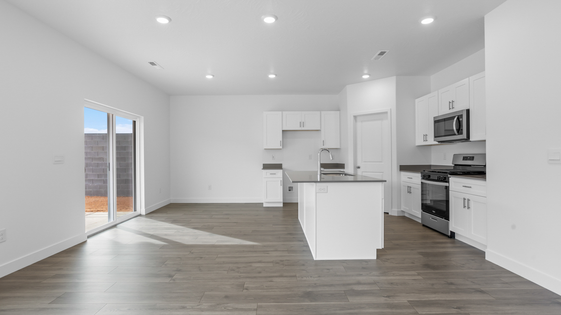 View of dining room with sliding glass door out to backyard, spacious kitchen with an in breakfast bar sink, stainless steel appliances