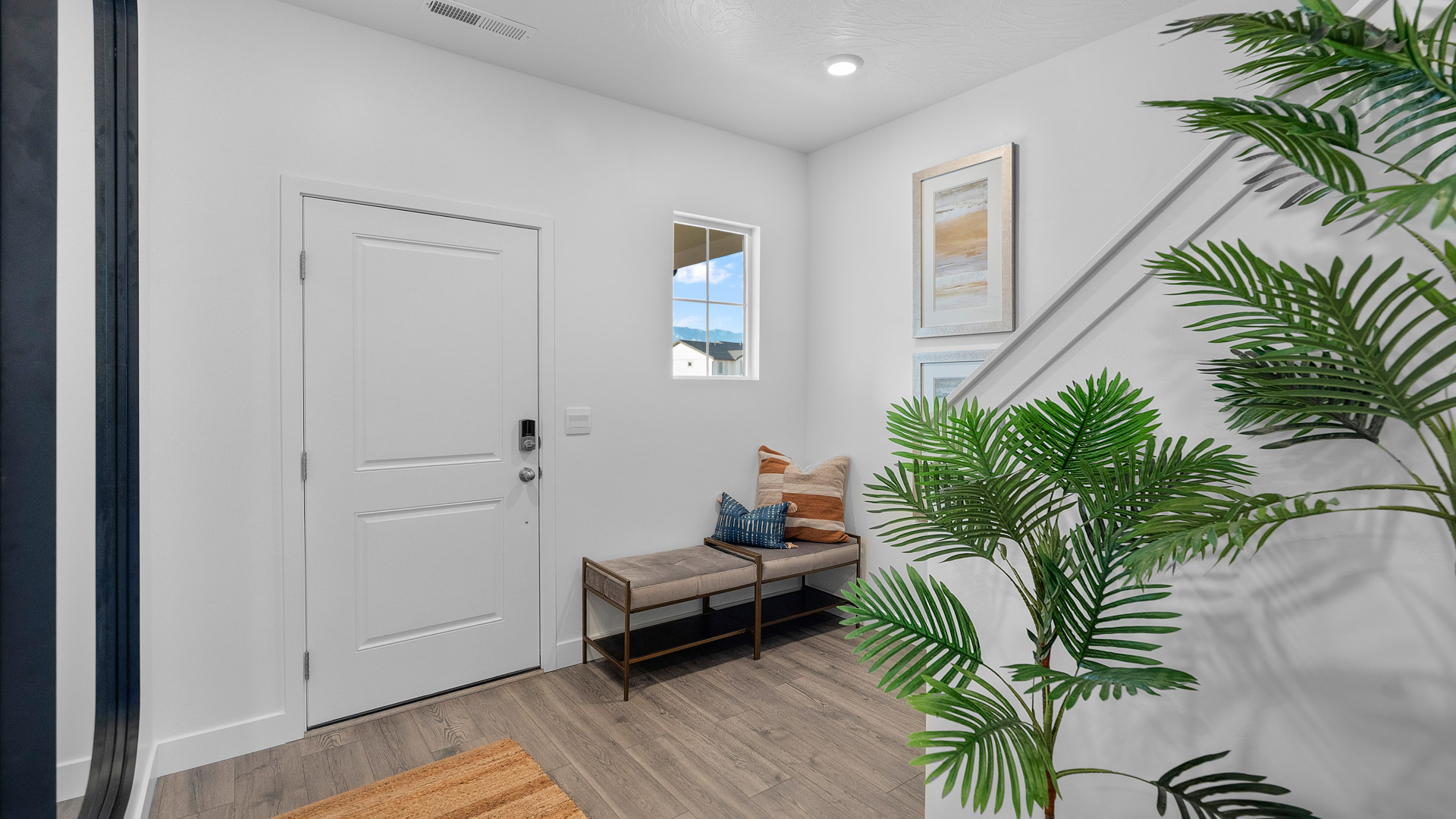 Entry of the home with a wide staircare leading to the second floor, and an extra-wide hallway leading to the main floor living area.