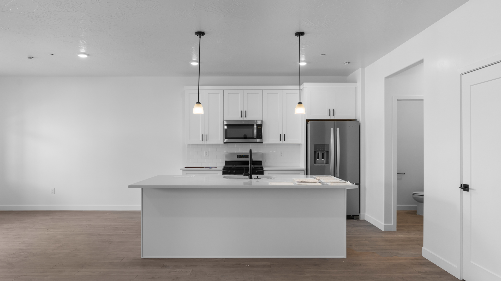 Closer look at kitchen with pendant lights, island, and stainlesss steel appliances.