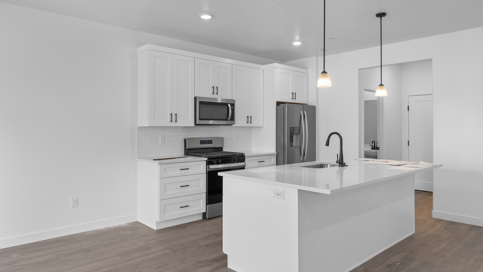 Kitchen featuring quartz countertops, pendant lighting, stainless steel appliances, and kitchen island.