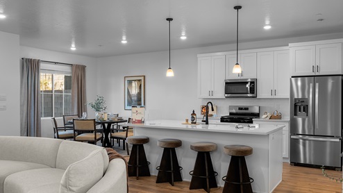 Kitchen with kitchen island and white cabinets and countertops with stainless steel appliances.