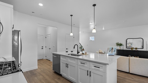 Kitchen with kitchen island and white cabinets and countertops with stainless steel appliances.