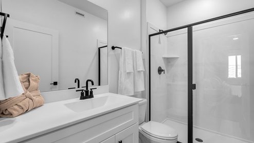 Bathroom with white cabinets and countertops and shower surround.