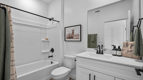 Bathroom with white cabinets and countertops and shower surround.