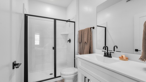 Bathroom with white cabinets and countertops and shower surround.