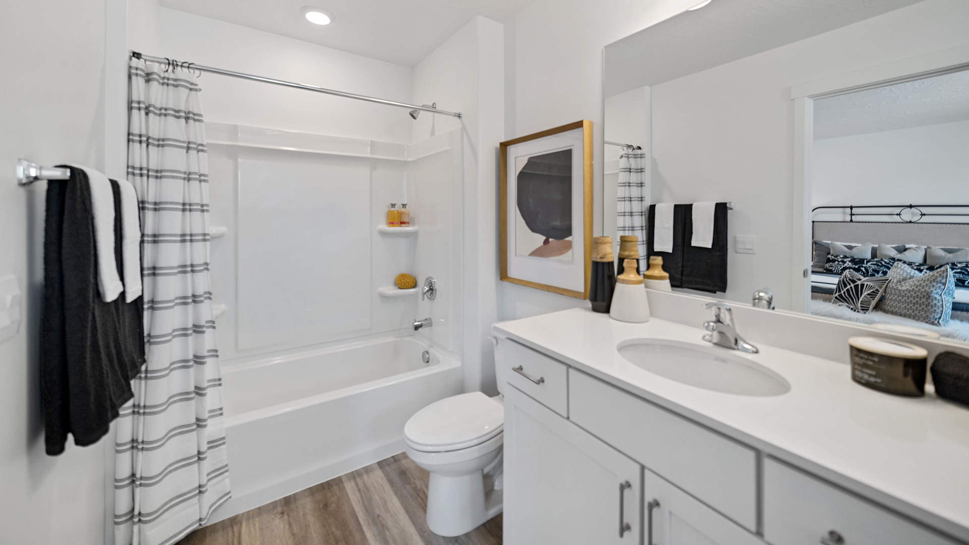 Primary bathroom with gray countertops and white cabinets and shower surround.