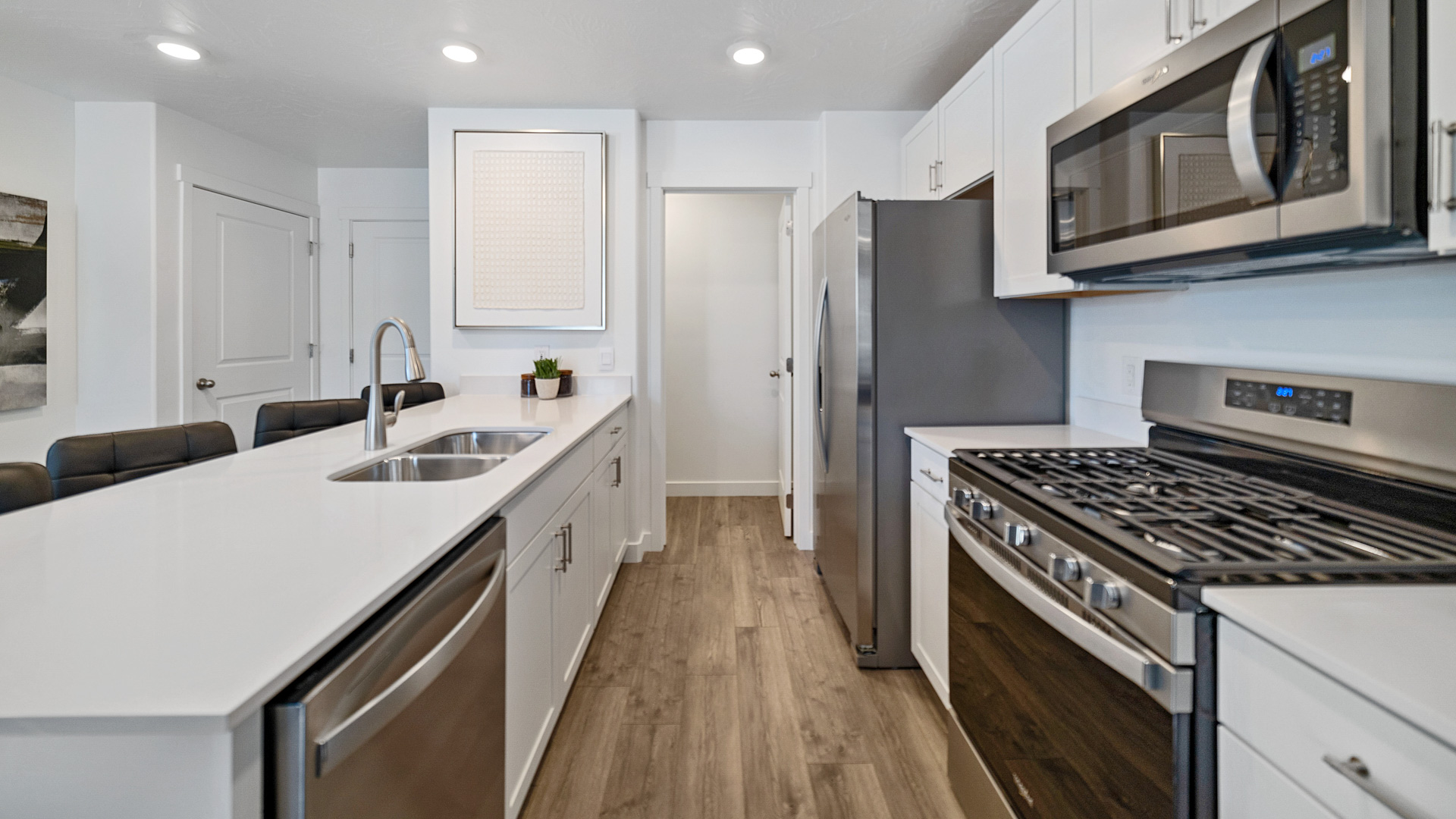 Living room into the kitchen space with white cabinets and gray countertops showcasing stairs near entryway.