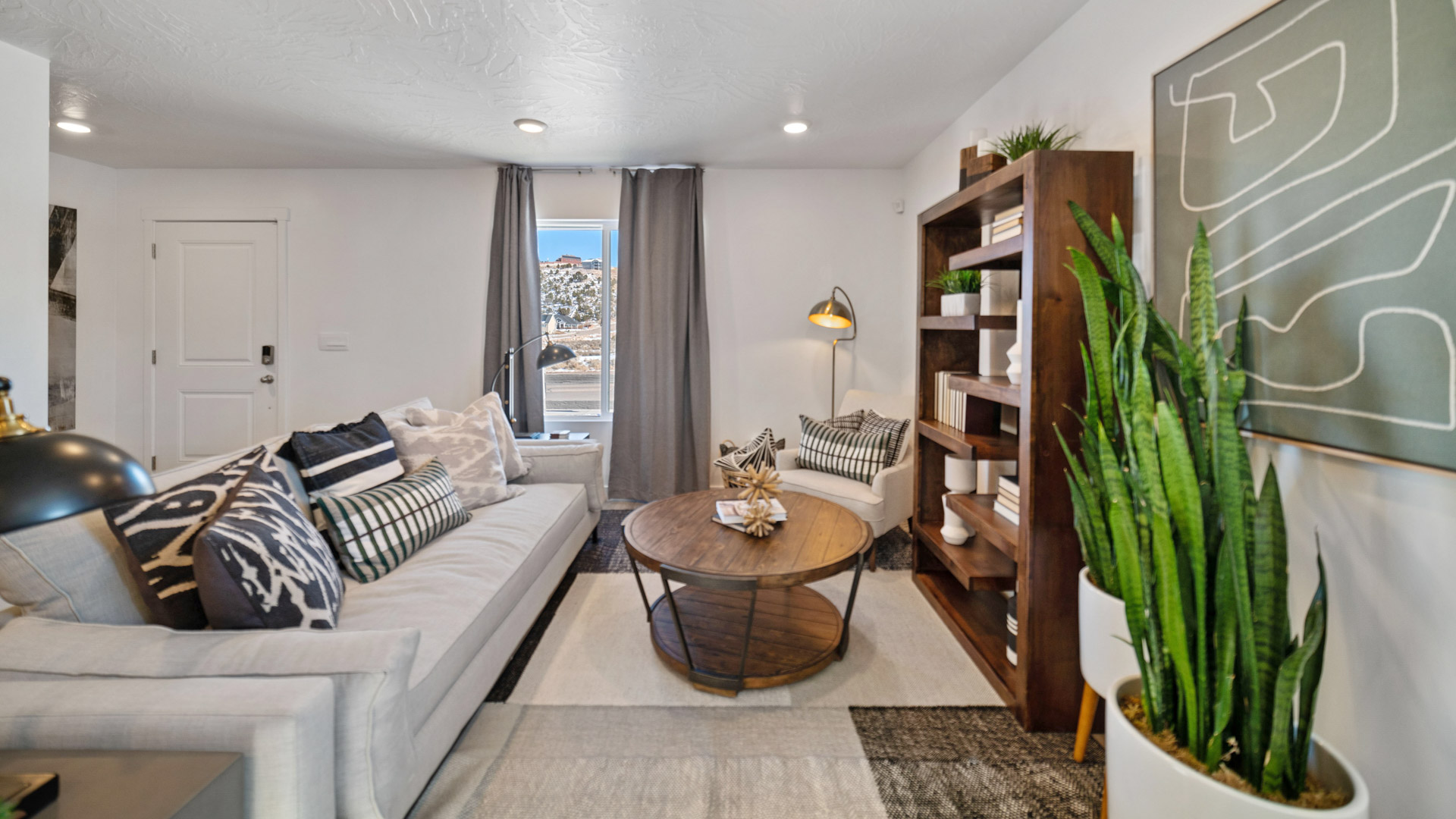 Living room into the kitchen space with white cabinets and gray countertops.