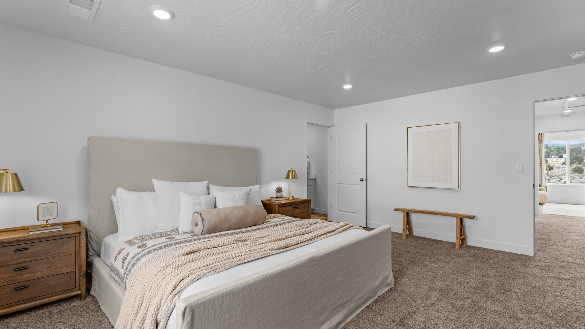 Spacious primary bedroom with a large window and door leading into the en suite full sized bathroom.