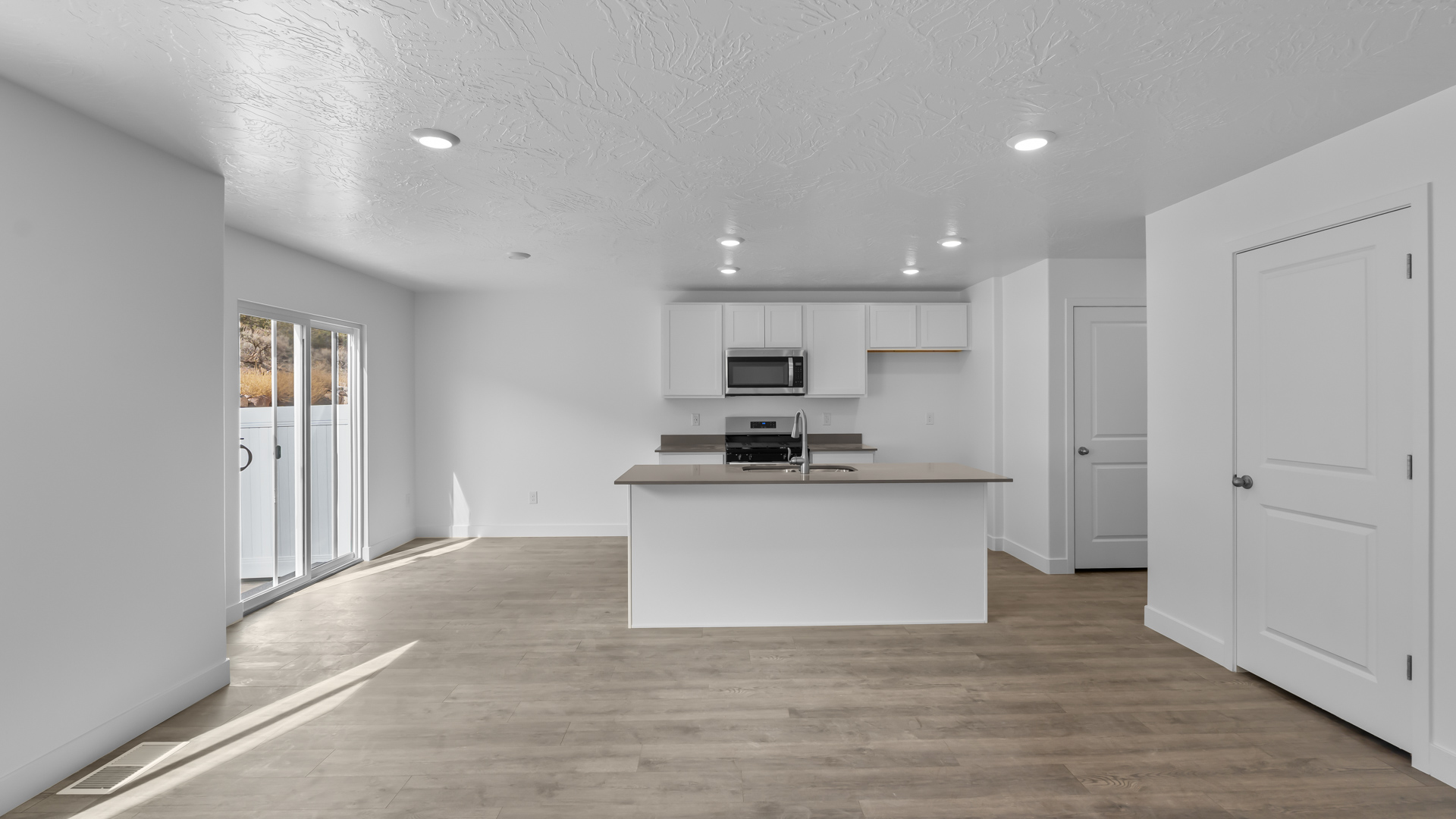 Kitchen space with island featuring white cabinets and gray countertops.