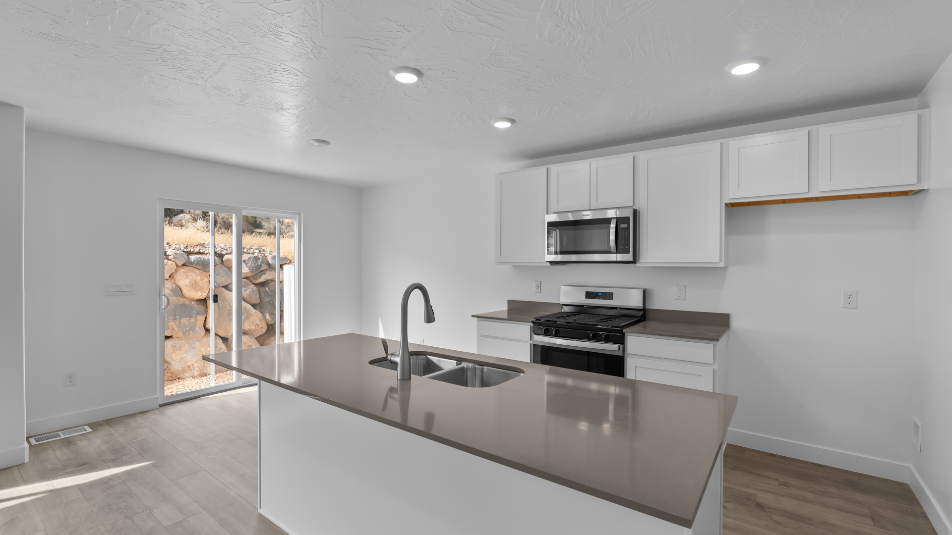 Kitchen space with island featuring white cabinets and gray countertops.