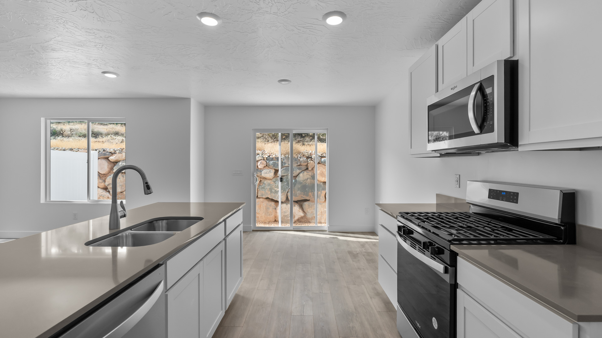 Kitchen space with island featuring white cabinets and gray countertops.