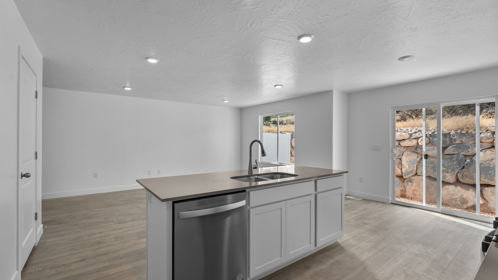 Kitchen space with island featuring white cabinets and gray countertops.