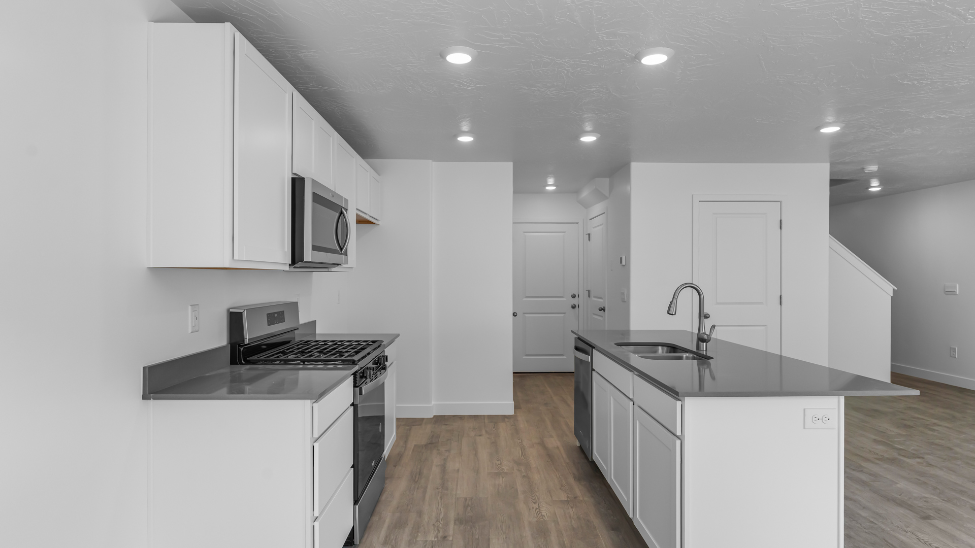 Kitchen space with island featuring white cabinets and gray countertops.