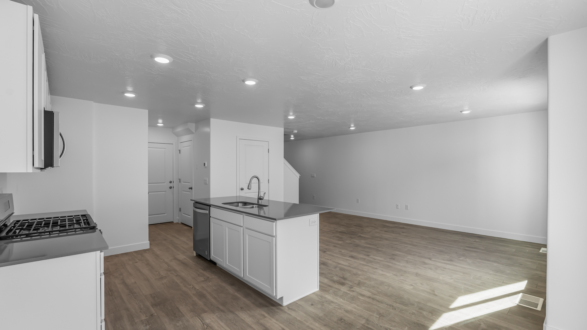 Kitchen space with island featuring white cabinets and gray countertops.