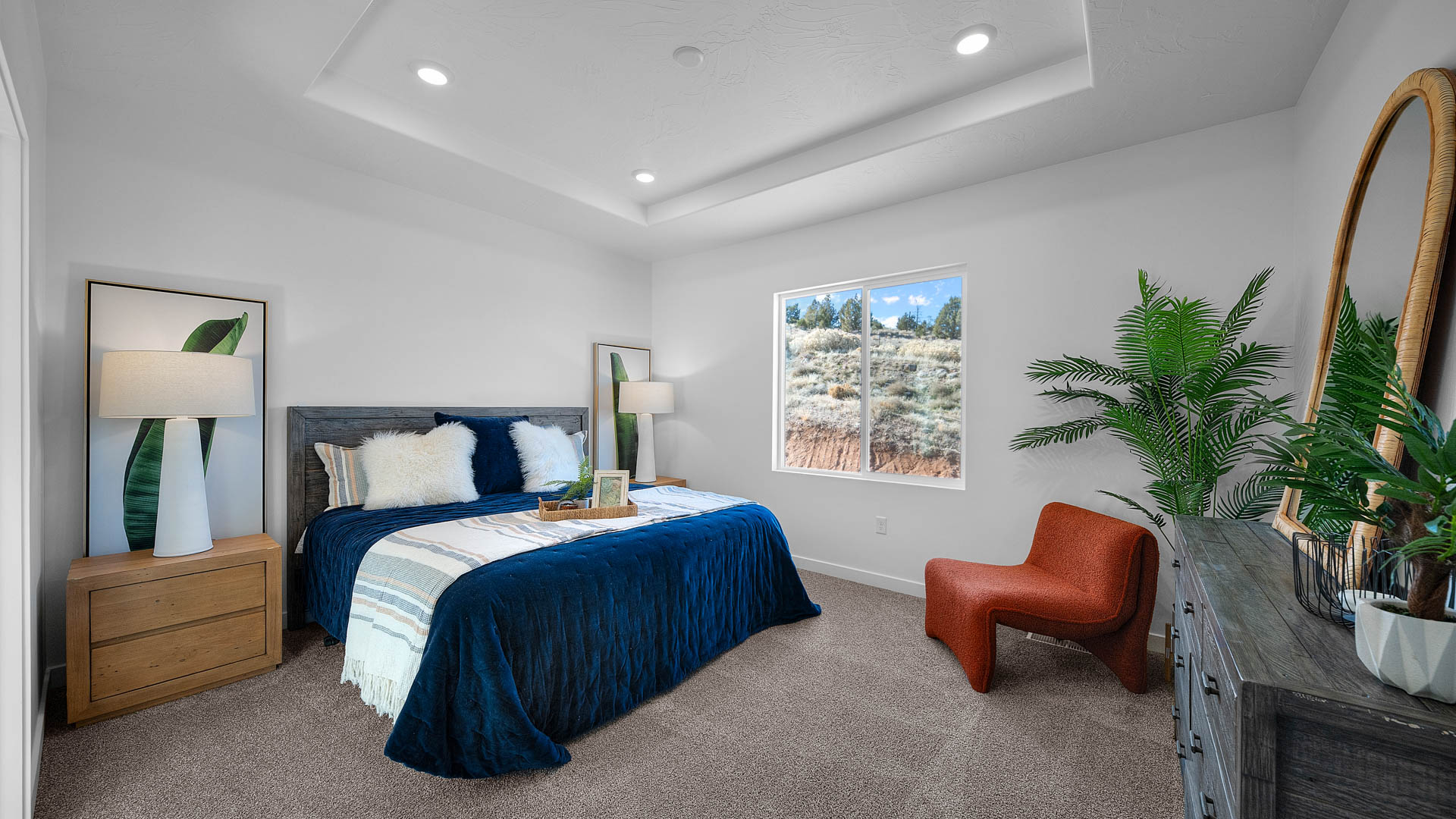 Primary bedroom with tray ceiling and large window.