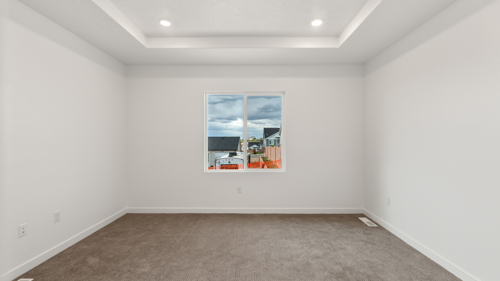 Primary bedroom with large window and tray ceilings.