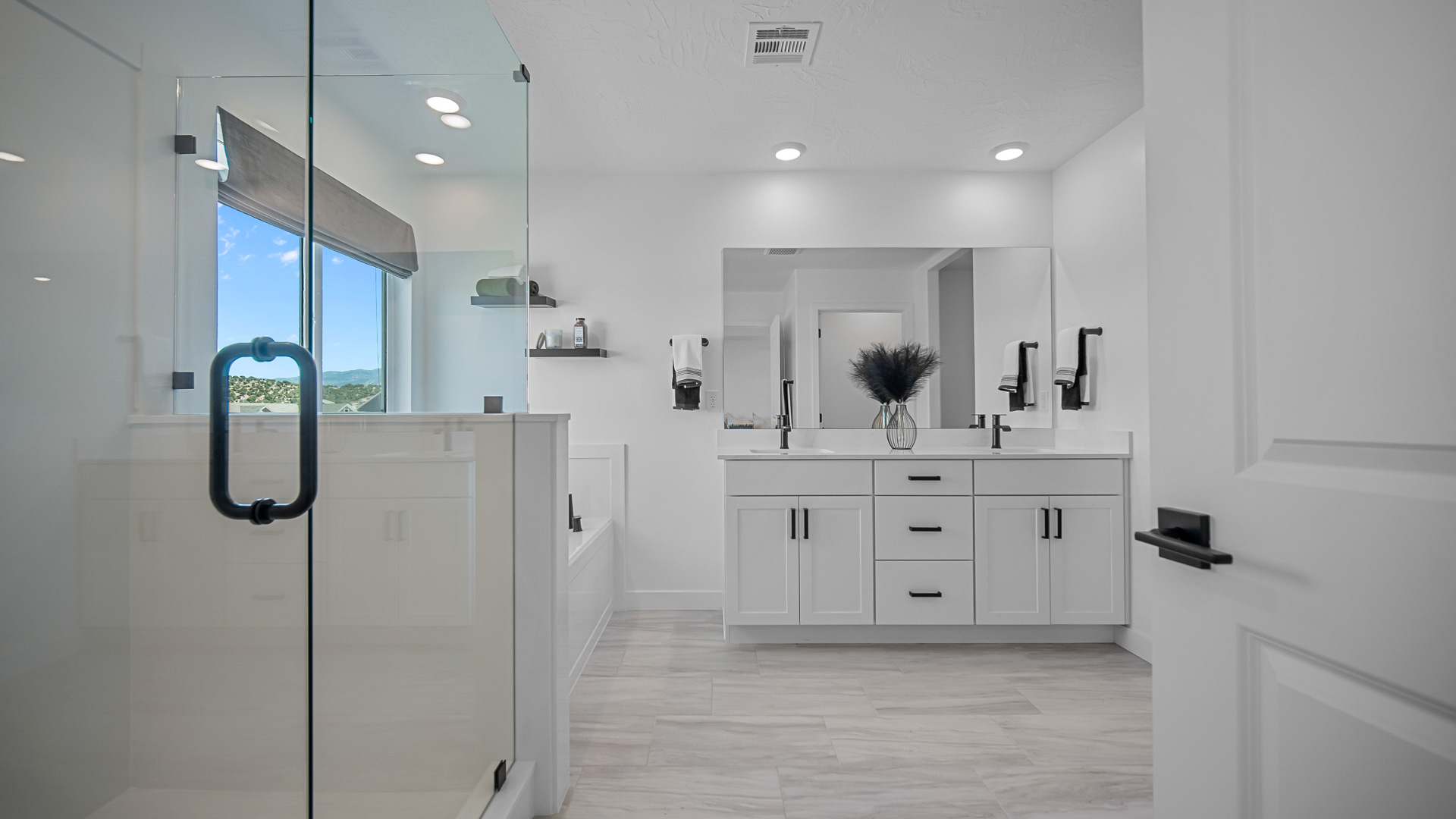 Primary bathroom with double sink vanity, tub, and glass shower.