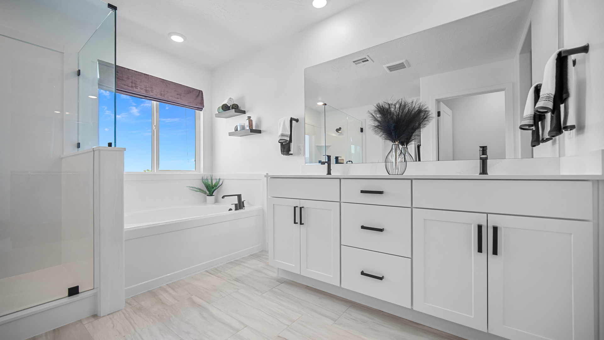 Primary bathroom with double sink vanity, tub, and glass shower.