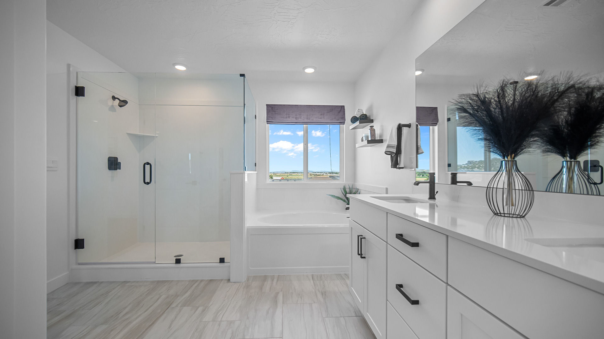 Primary bathroom with double sink vanity, tub, and glass shower.