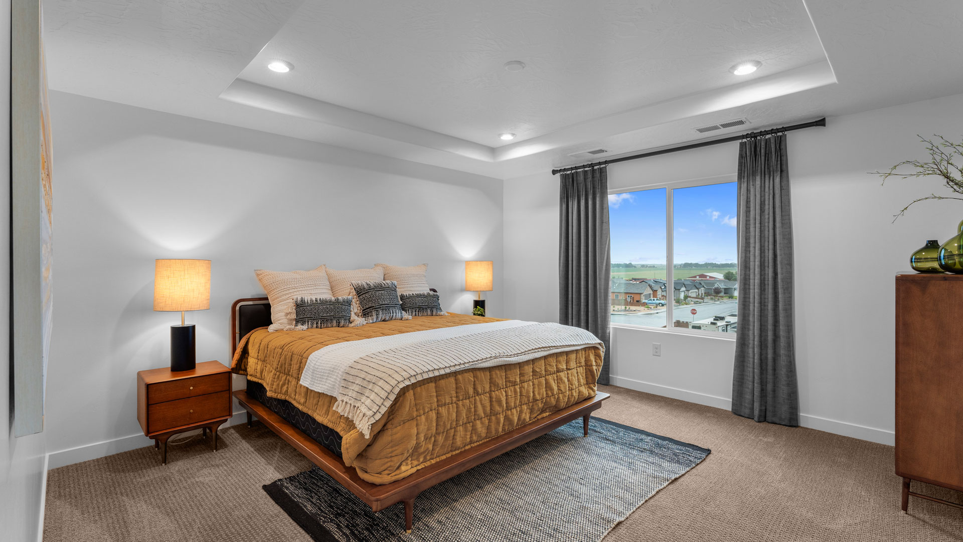 Primary bedroom with tray ceiling and large window.