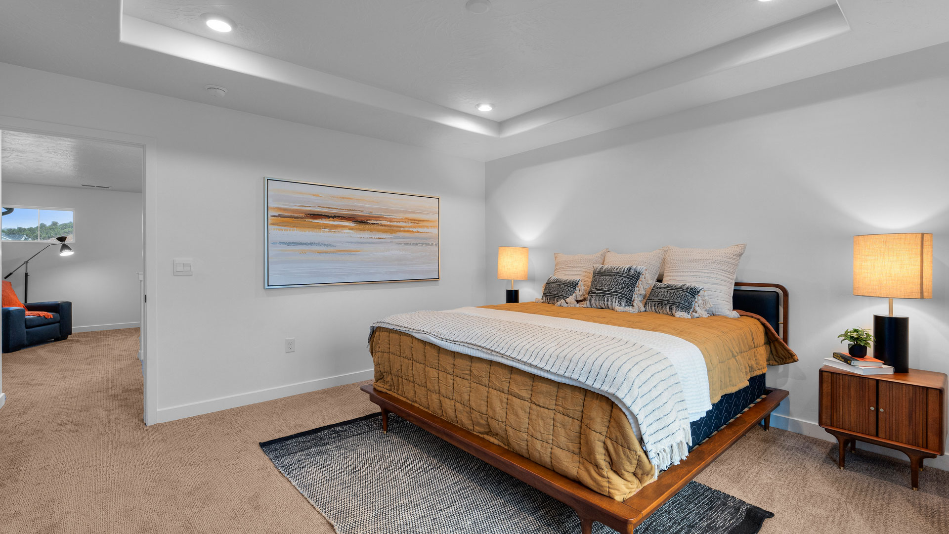 Primary bedroom with tray ceiling and large window.