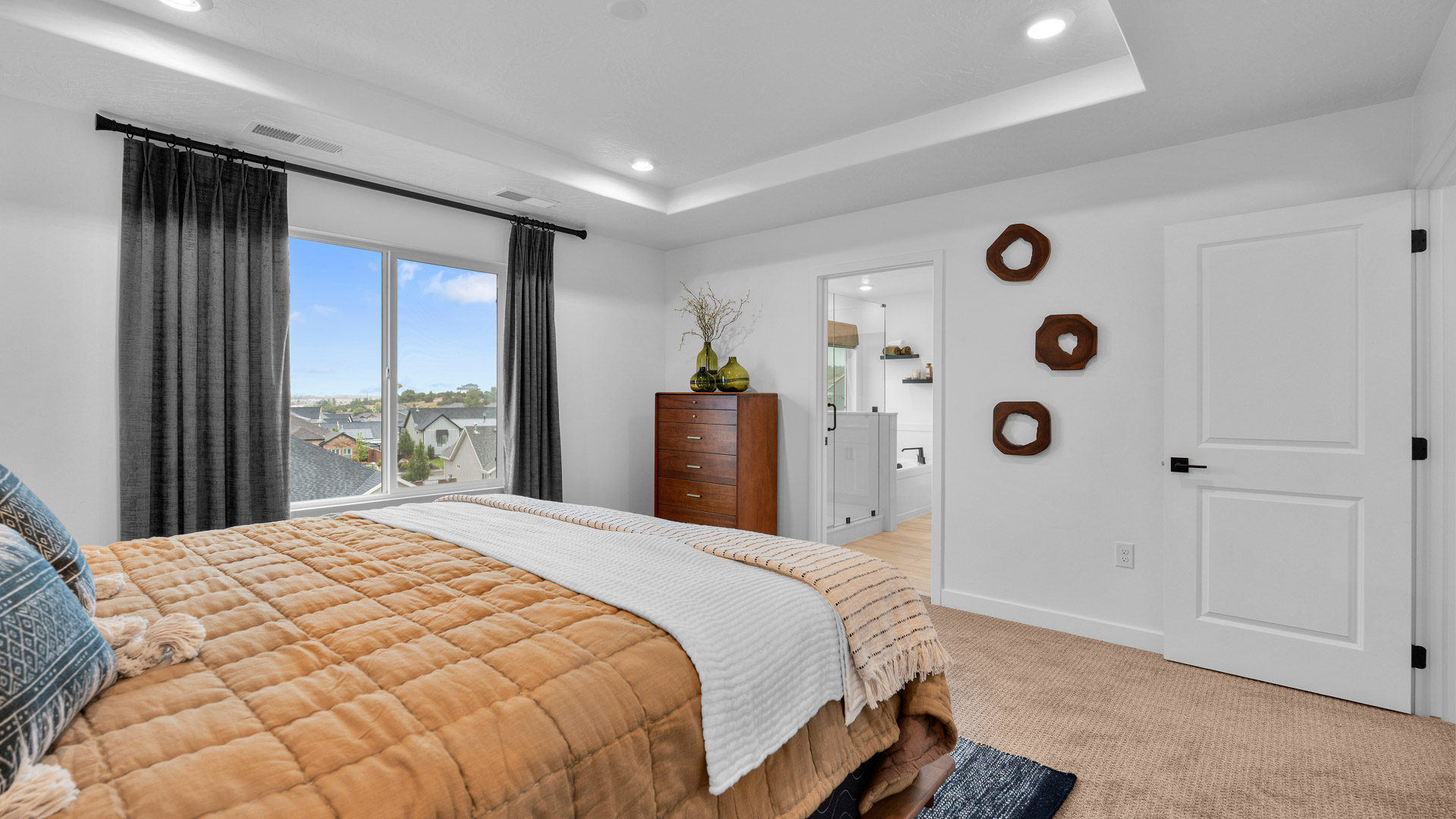Primary bedroom with tray ceiling and large window.