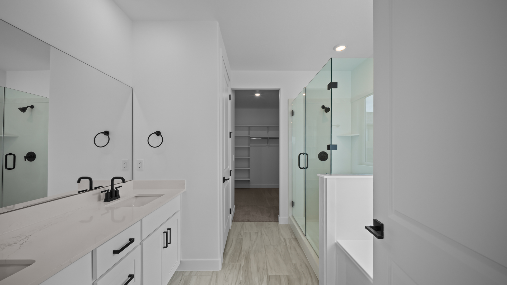 Primary bathroom with double sink vanity, glass shower, tub, and vanity.