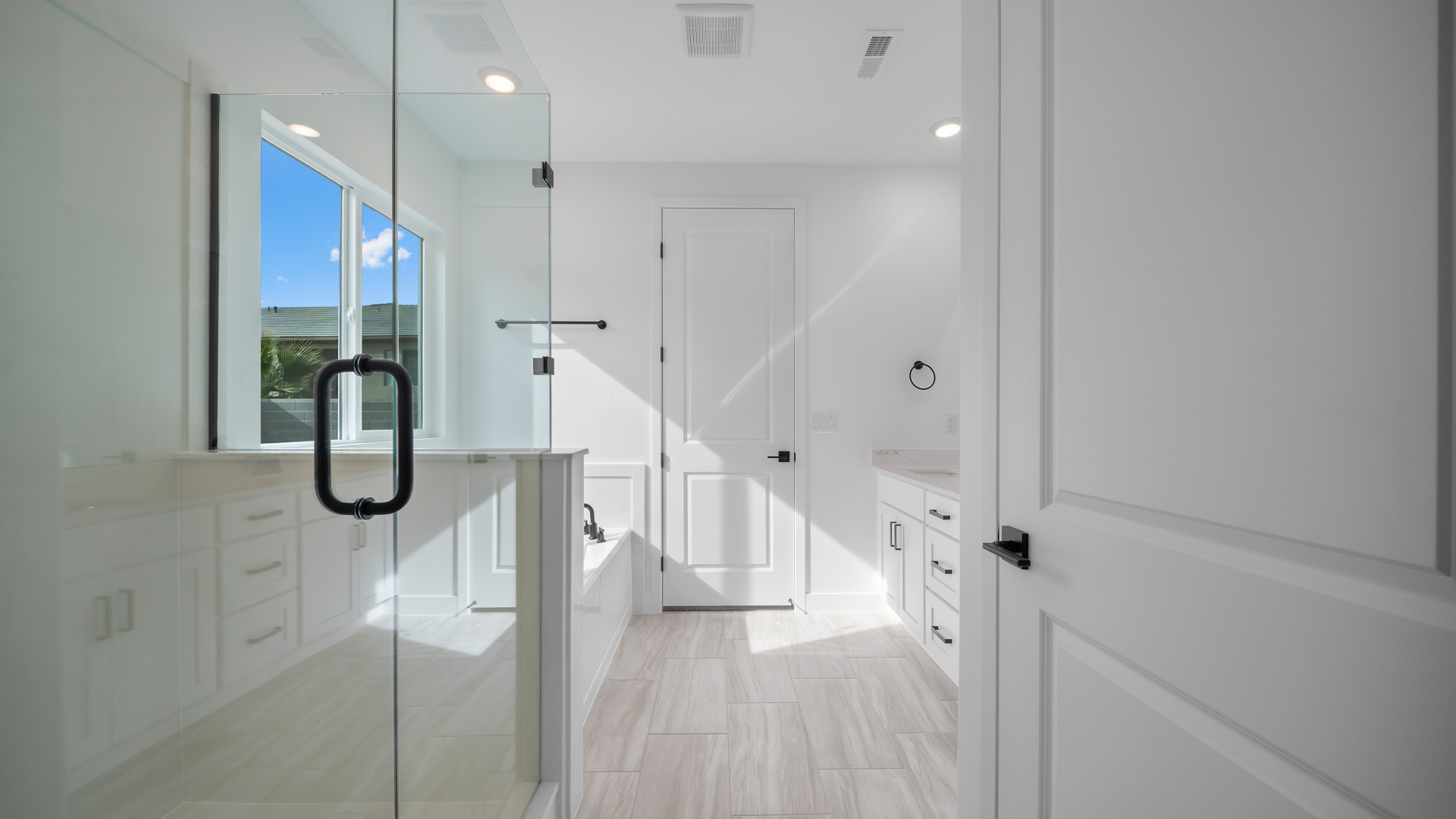 Primary bathroom with double sink vanity, glass shower, tub, and vanity.