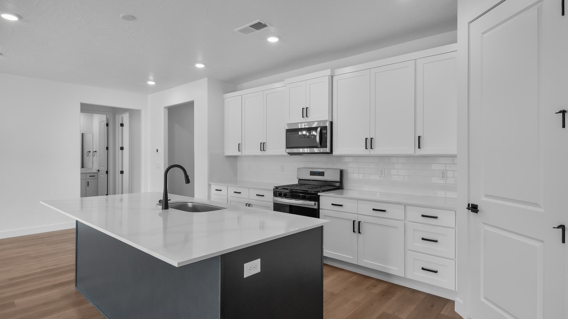 Kitchen with two-tone cabinets, kitchen sink at kitchen island, and stainless steel appliances.