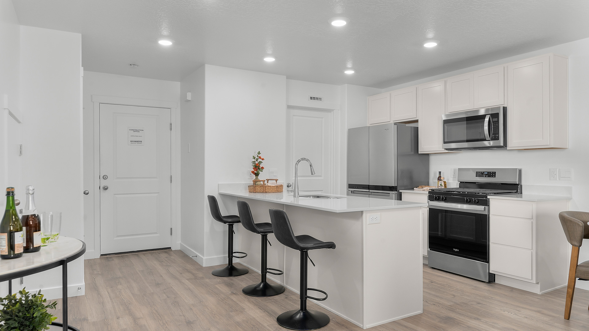 Kitchen space with peninsula featuring barstools, sink, kitchen cabinets, and appliances.