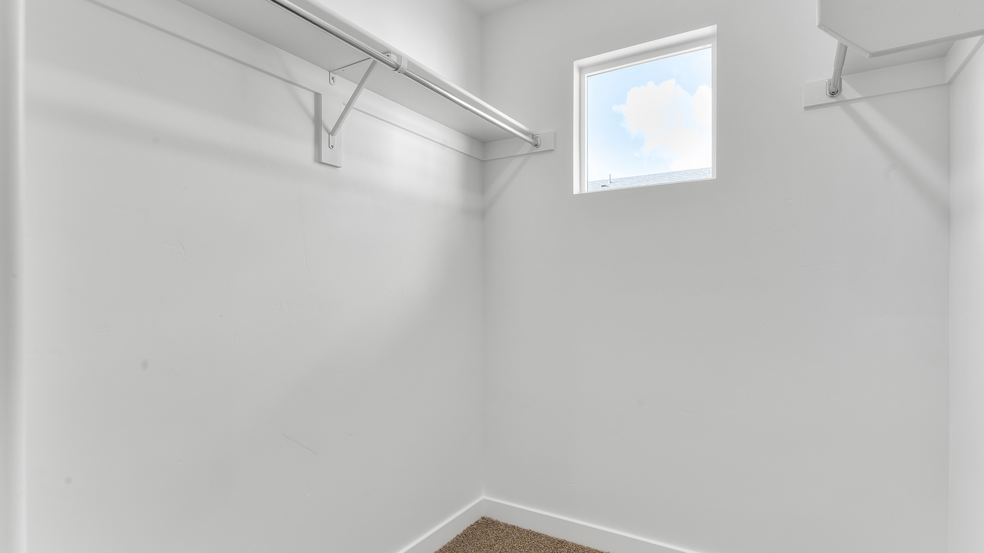 Spacious walk-in closet with square window off of bathroom.