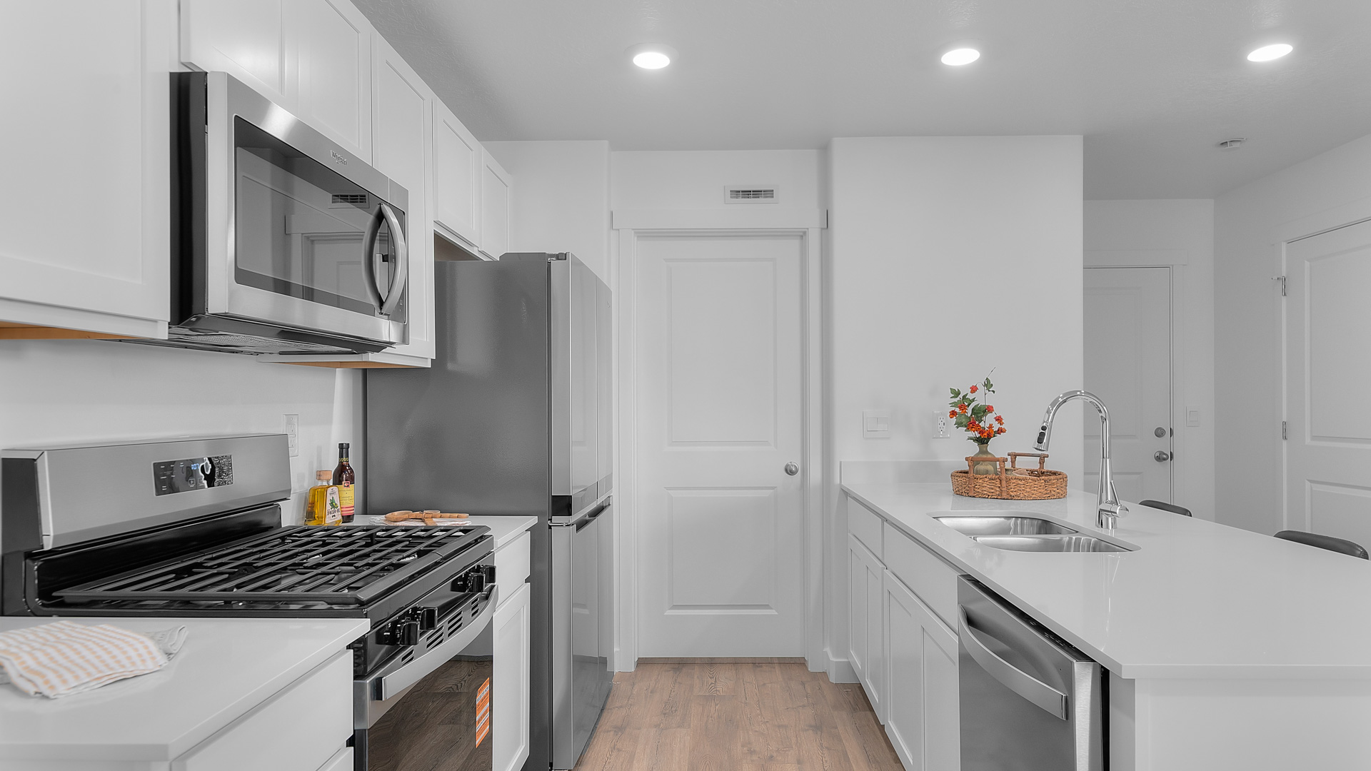 Kitchen space with peninsula featuring barstools, sink, kitchen cabinets, and appliances.